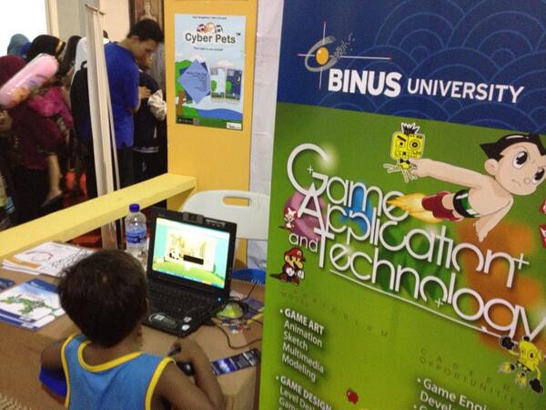 Seorang adik kecil sedang bermain aplikasi game Garuda Kids di stand SoCS